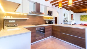 Una cocina moderna con armarios de madera, horno empotrado e iluminación colgante.