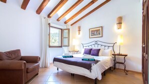 Un dormitorio con una cama, un sofá marrón y un ventanal con cortinas.