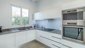 Eine moderne Küche mit weißen Schränken, einem Kombi-Backofen und einem großen Fenster.