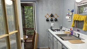 Une cuisine de taille réduite, équipée d’un évier, d’une cuisinière et dotée d’un plancher en bois.