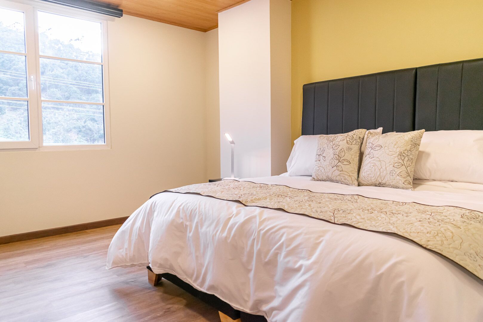 Un dormitorio con una cama, una lámpara de noche y una ventana.