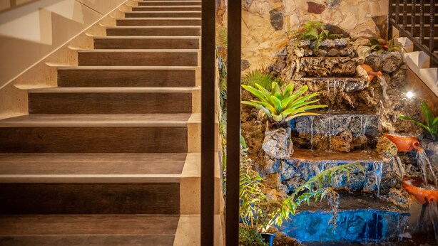 Una escalera de madera con un muro de piedra y una pequeña cascada.