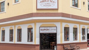 Un hotel con un letrero que dice "ORIGENES Hotel Boutique" y otro letrero que anuncia "SUPERSONA Artesanal Artesanías".