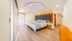 Un dormitorio moderno con una cama grande, piso de madera, una lámpara en el techo y una ventana con persianas.