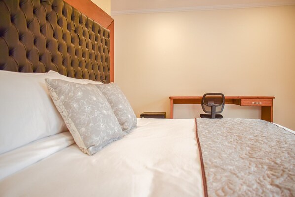 Una habitación de hotel con una cama grande, un escritorio de madera y una silla.