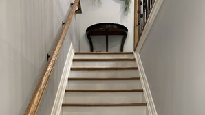 A staircase with wooden steps and white walls. - Ambiance by the Falls Cozy Suite (Niagara Falls)