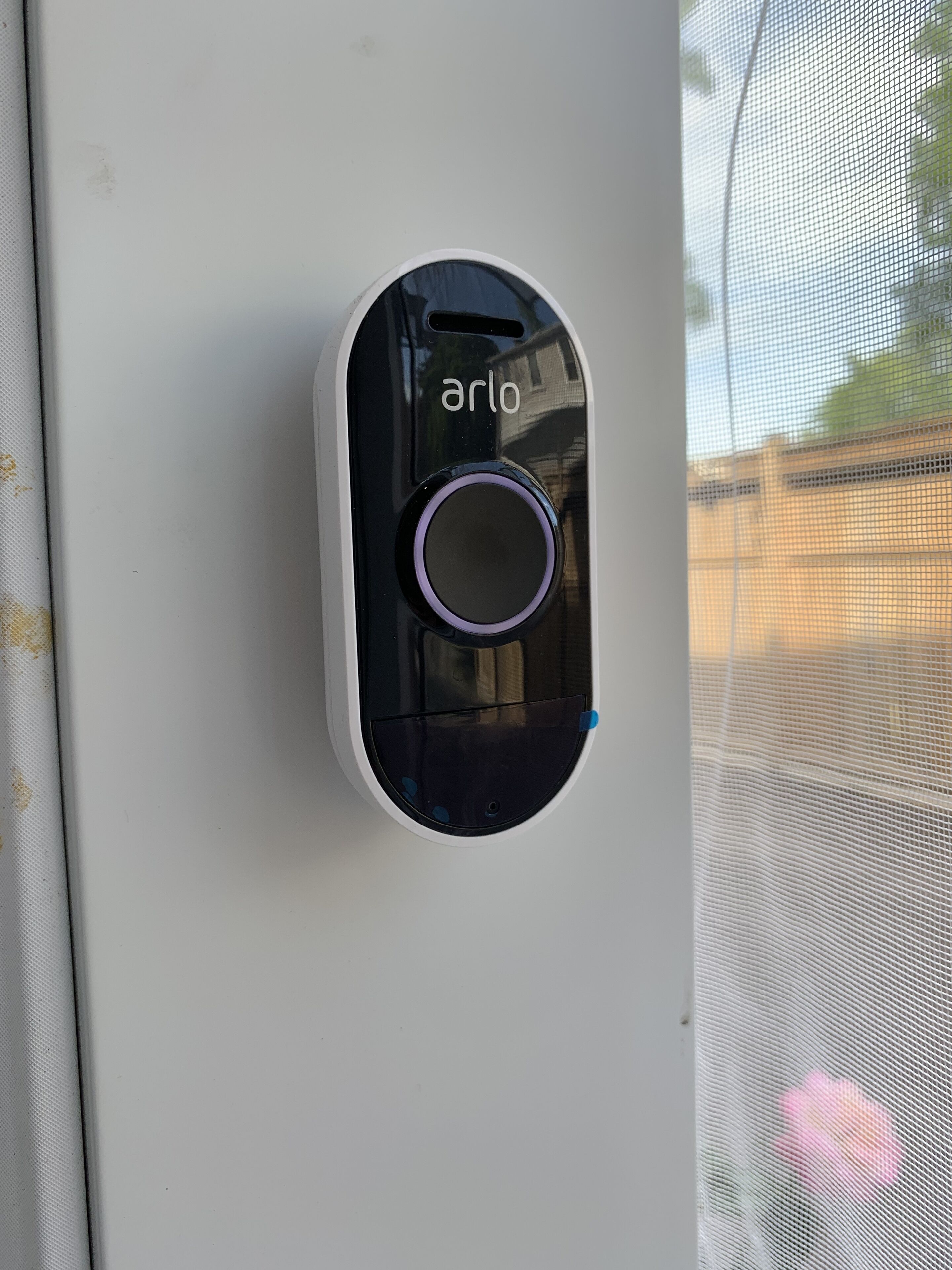 A device labeled "arlo" mounted on a white surface, likely a window or door.