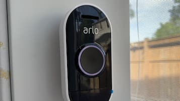 A device labeled "arlo" mounted on a white surface, likely a window or door.