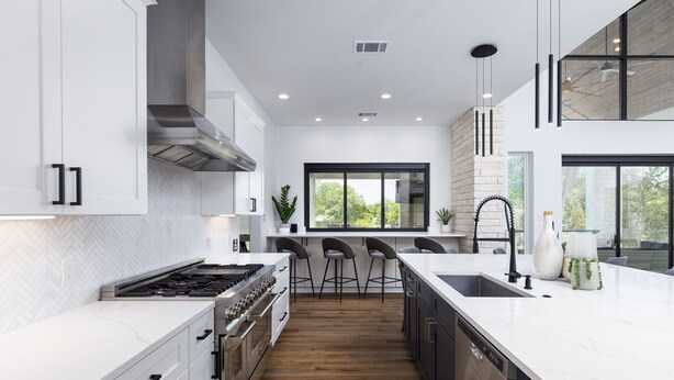 A modern kitchen with white cabinetry, a large island, and a view of the outdoors. - Lakefront 5BR w/ Pool, Hot Tub & Game Room. Sleeps 24. Family-Friendly (Seguin)