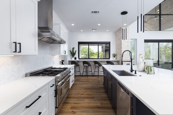 A modern kitchen with white cabinetry, a large island, and a view of the outdoors.