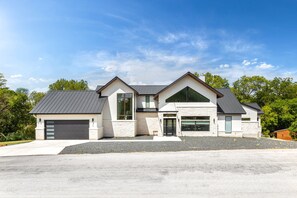 A modern two-story house with a garage, large windows, and a sloped roof.