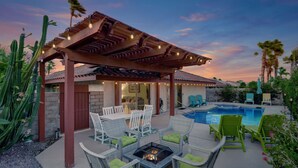 Ein überdachter Patio-Bereich mit Gartenmöbeln, einer Feuerstelle und einem Pool.