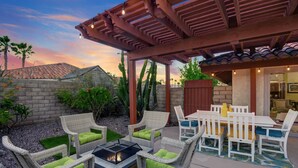 Eine Terrassengaststätte mit Korbmöbeln, einer Feuerstelle und einer Pergola.