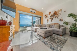 A modern living room with a large sofa, a coffee table, and a world map on the wall.