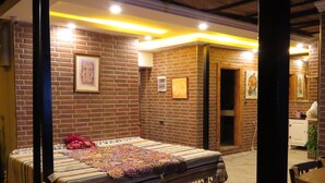Una habitación con cama, paredes de ladrillo y cuadros enmarcados.