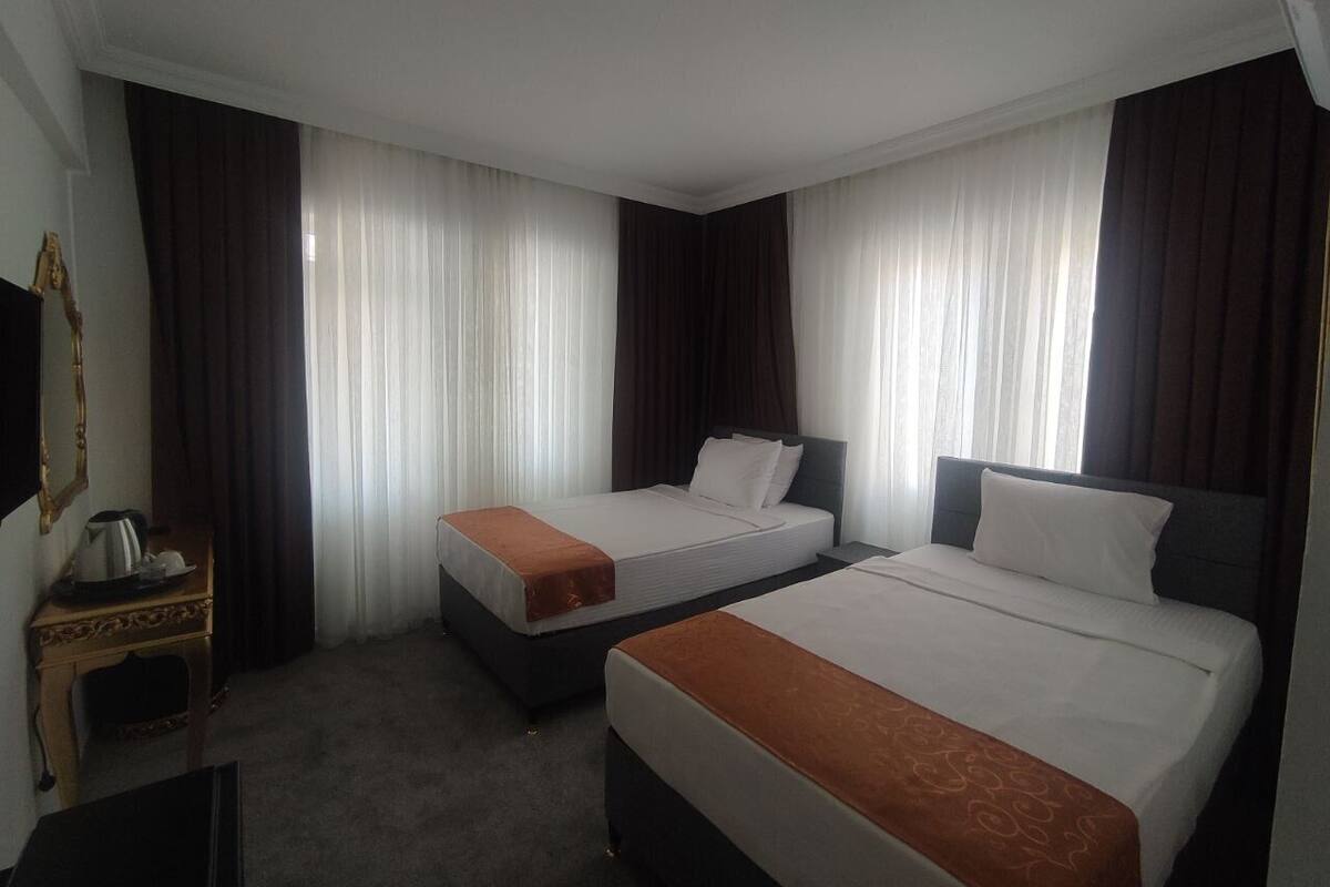 Ein Hotelzimmer mit zwei Betten, einem kleinen Tisch mit Wasserkocher und einem Spiegel an der Wand.