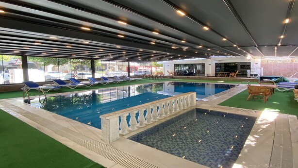 Una piscina interior con múltiples carriles, sillas de descanso y un área de estar con mesas y sillas.