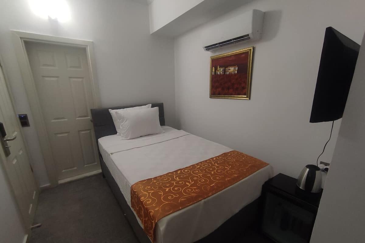 Ein Hotelzimmer mit Bett, Fernseher, Heizung und einer Tür.