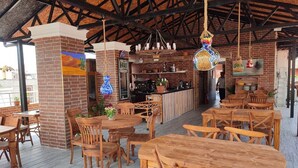 Un restaurante con mesas y sillas de madera, un muro de ladrillo y adornos colgantes.