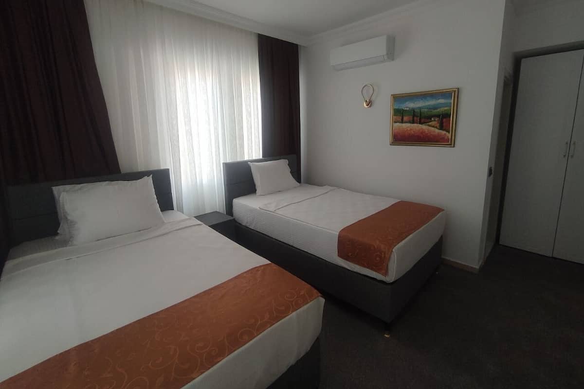 Ein Hotelzimmer mit zwei Betten, einem Bild an der Wand und einer Klimaanlage.