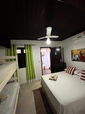 A bedroom with bunk beds, a single bed, a ceiling fan, and a painting on the wall. - Pousada Passarte Biquinha (Cairu)