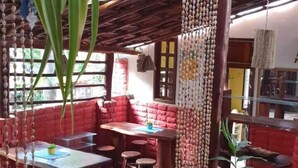 Un espacio interior con vigas de madera, pared de ladrillo rojo y una mesa con sillas.
