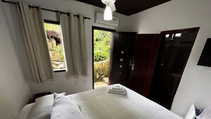 Un dormitorio con cama, cortinas, un equipo de aire acondicionado y vistas al exterior.