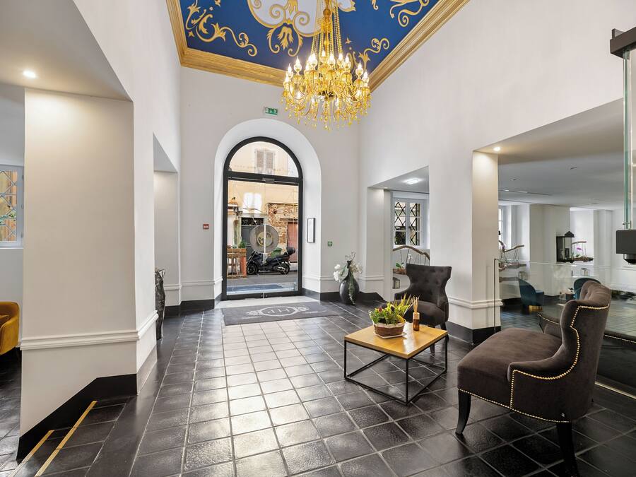 Un hall d’hôtel avec un lustre, un comptoir d’accueil et un espace salon.