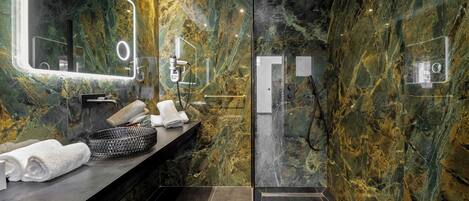 Un baño moderno con tocador de mármol, un espejo grande y cabina de ducha con mampara de vidrio.