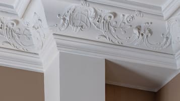 Techo blanco con molduras ornamentales y pared beige lisa.