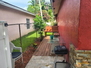 Une terrasse avec un barbecue, une chaise et une table.