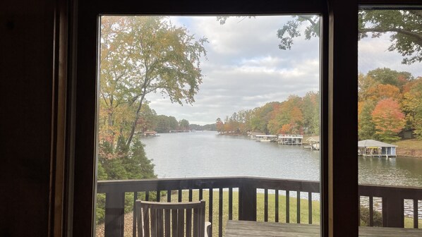 A view from a window overlooking a lake with boats, surrounded by trees with autumn foliage.