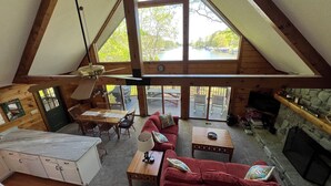Een ruime loft-achtige kamer met een eethoek, een rode bank en een stenen open haard.