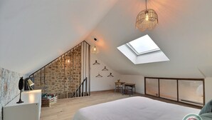 A loft bedroom with a skylight, a wooden staircase, a desk, and a bed. - Victor - RIVES DU COUESNON (RIVES-DU-COUESNON)