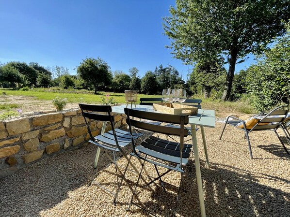 An outdoor dining area with a stone wall, a table with chairs, and a bench. - Victor – RIVES DU COUESNON (RIVES-DU-COUESNON)