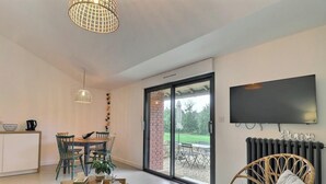 A modern living room with a dining area, a sofa, a coffee table, and a TV mounted on the wall. - Victor - RIVES DU COUESNON (RIVES-DU-COUESNON)