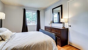 A bedroom with a bed, a dresser, a mirror, and a window with curtains. - Cozy Modern Single Family 5BD 2BA Home (Falls Church)