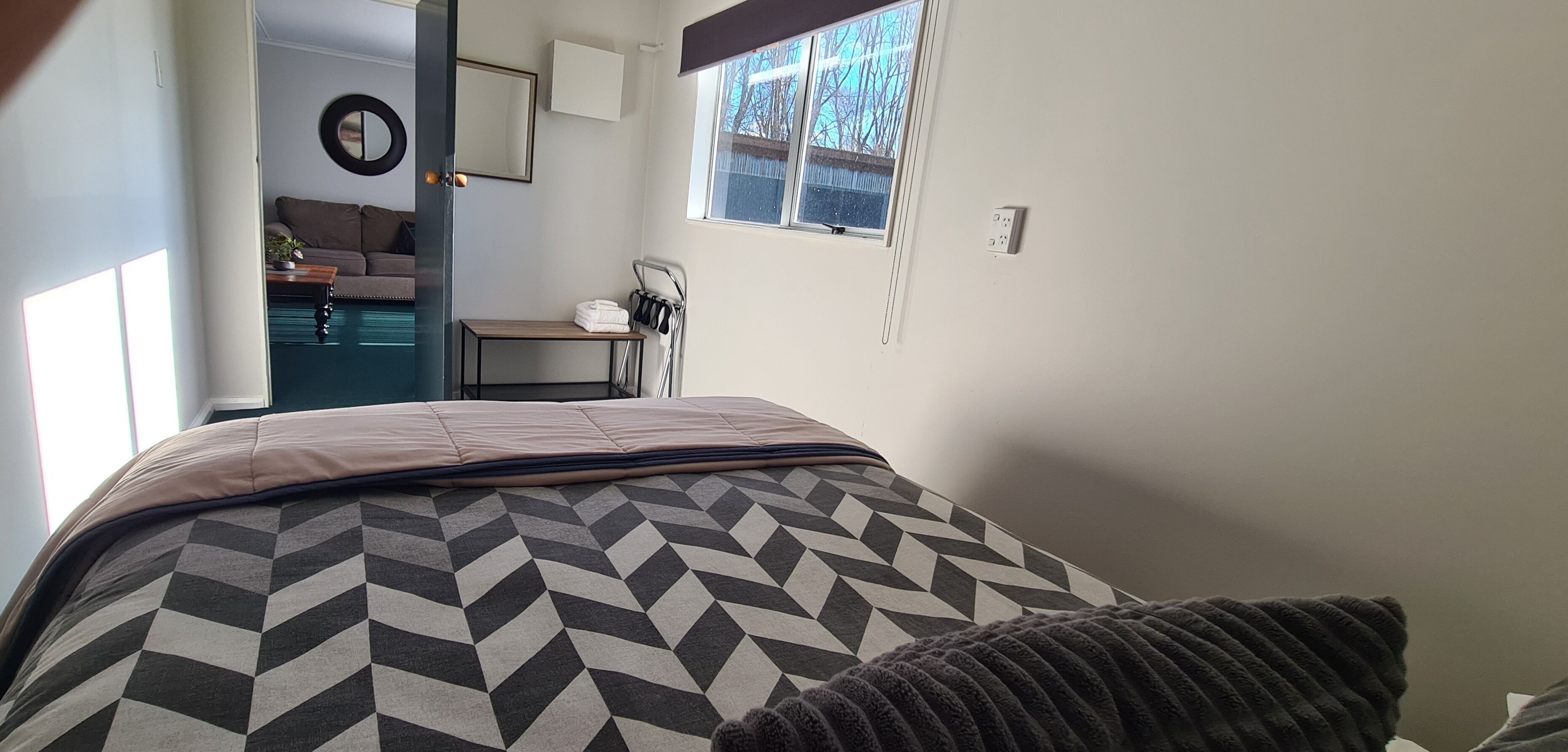 Una camera da letto con un letto, una finestra, uno specchio e una porta che dà su un'altra stanza.
