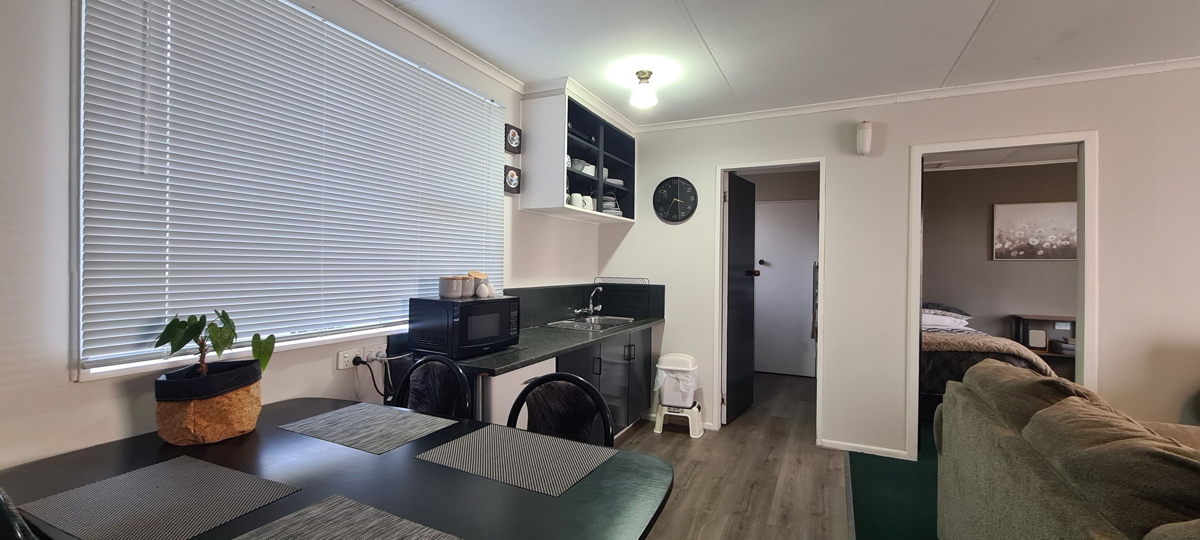 A compact living space with a kitchenette, a dining area, and a bedroom.