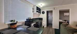 A compact living space with a kitchenette, a dining area, and a bedroom. - Kawakawa Cottage - lovely rural outlook. Convenient location to Manfield Park  (Feilding)