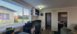 A compact living space with a kitchenette, a dining area, and a bedroom. - Kawakawa Cottage - lovely rural outlook. Convenient location to Manfield Park  (Feilding)