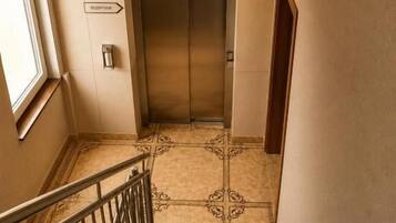 Een trap die leidt naar een lift, met een bord met de tekst receptie erboven.