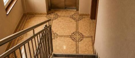 A staircase leading to an elevator with a reception sign above it.