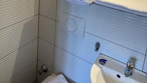 A bathroom with white tiled walls, a sink, and a mirror. - Hotel Pasa Paradies (Hanau)