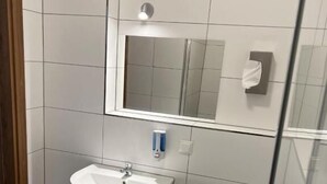 A bathroom with a white sink, a mirror, and a toilet. - Hotel Pasa Paradies (Hanau)