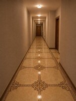 Un pasillo con suelo estampado, una puerta de madera al final y un accesorio de iluminación en el techo.