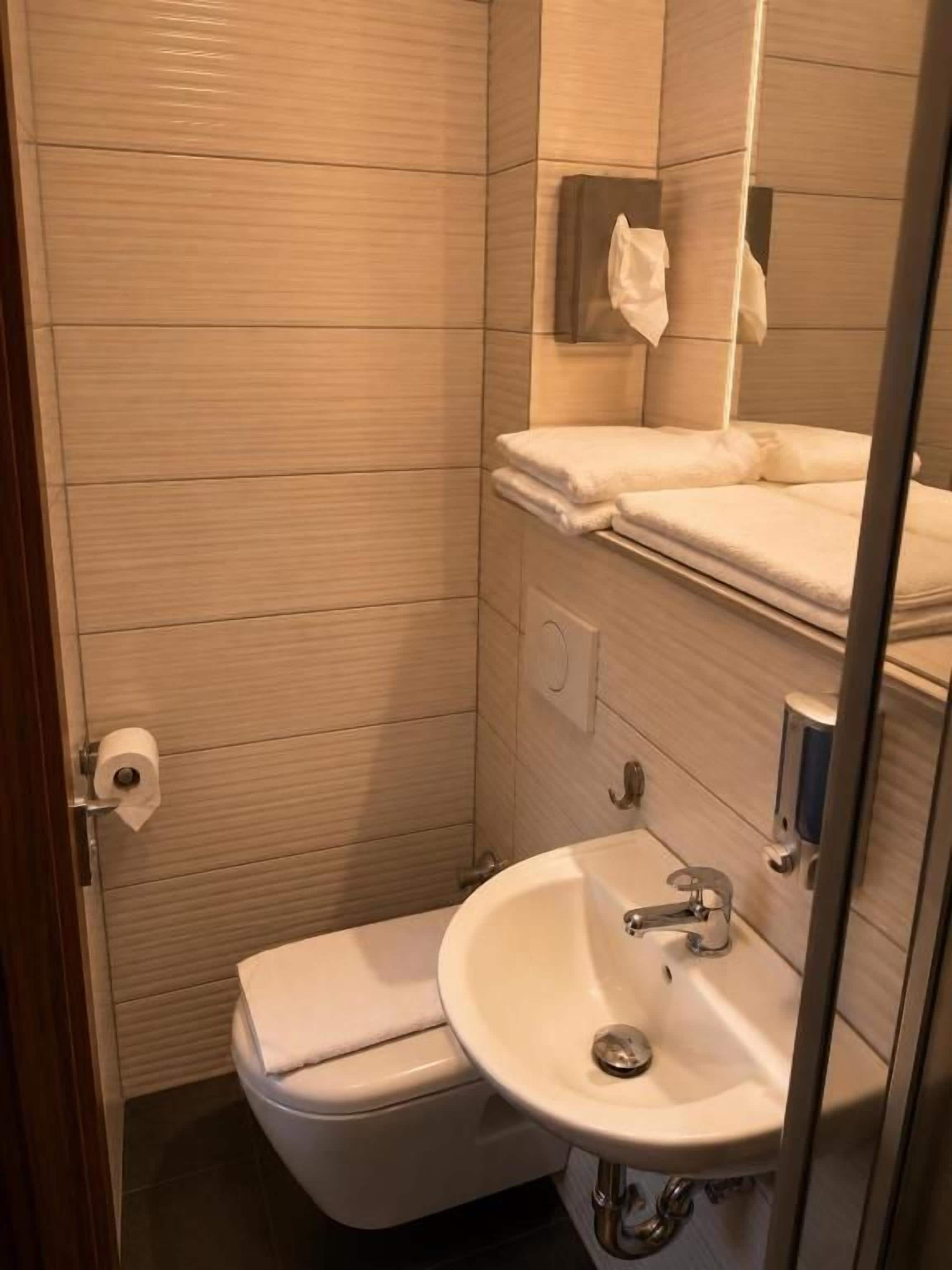 A small bathroom with a toilet, sink, and towel rack.