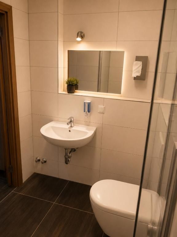 Een badkamer met een wit wastafel, een spiegel en een toilet.