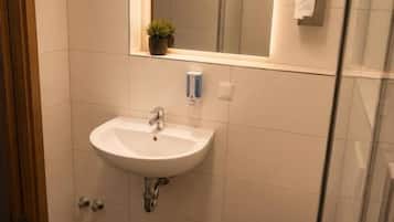 Een badkamer met een wit wastafel, een spiegel en een toilet.