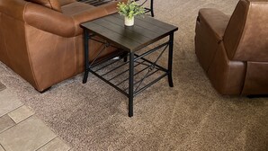 Een woonkamer met een bruine leren bank, twee bijpassende fauteuils, een salontafel en een televisie op een meubel.
